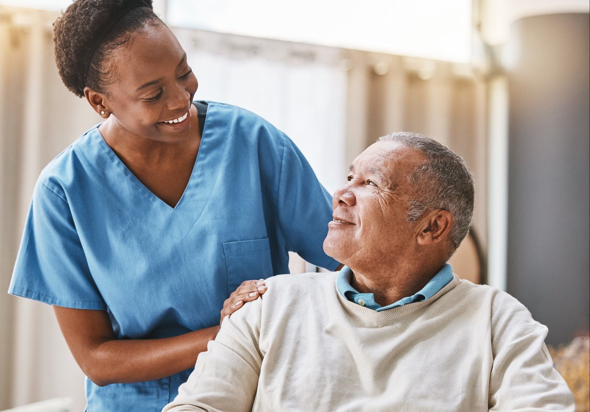 A female nurse smiling a senior citizen.