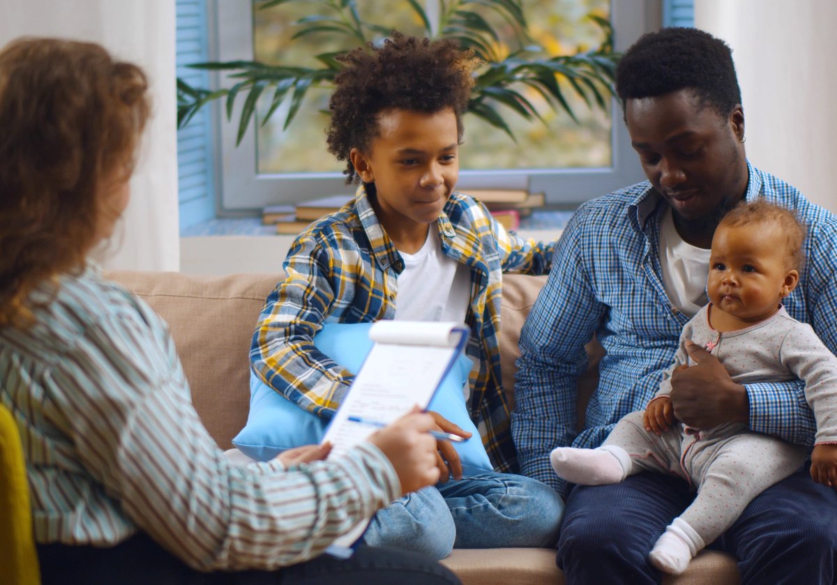 A family sitting on a couch across from a doctor during a medical appointment.